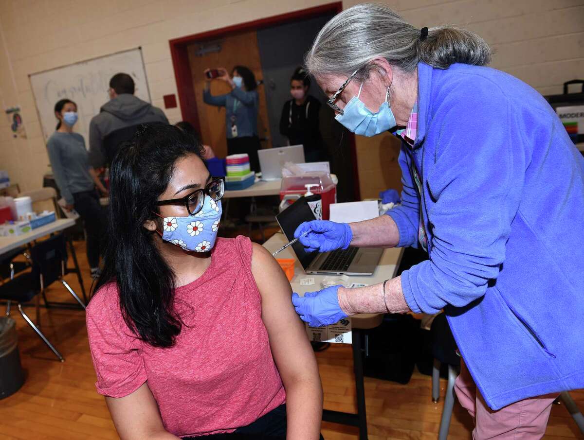 Rachana Shivawwamy, left, of New Haven receives a COVID-19 vaccination from APRN Grace Grajales during a walk-up vaccine clinic run by Fair Haven Community Health Care at the Wilbur Cross High School gymnasium in New Haven on April 22, 2021.
