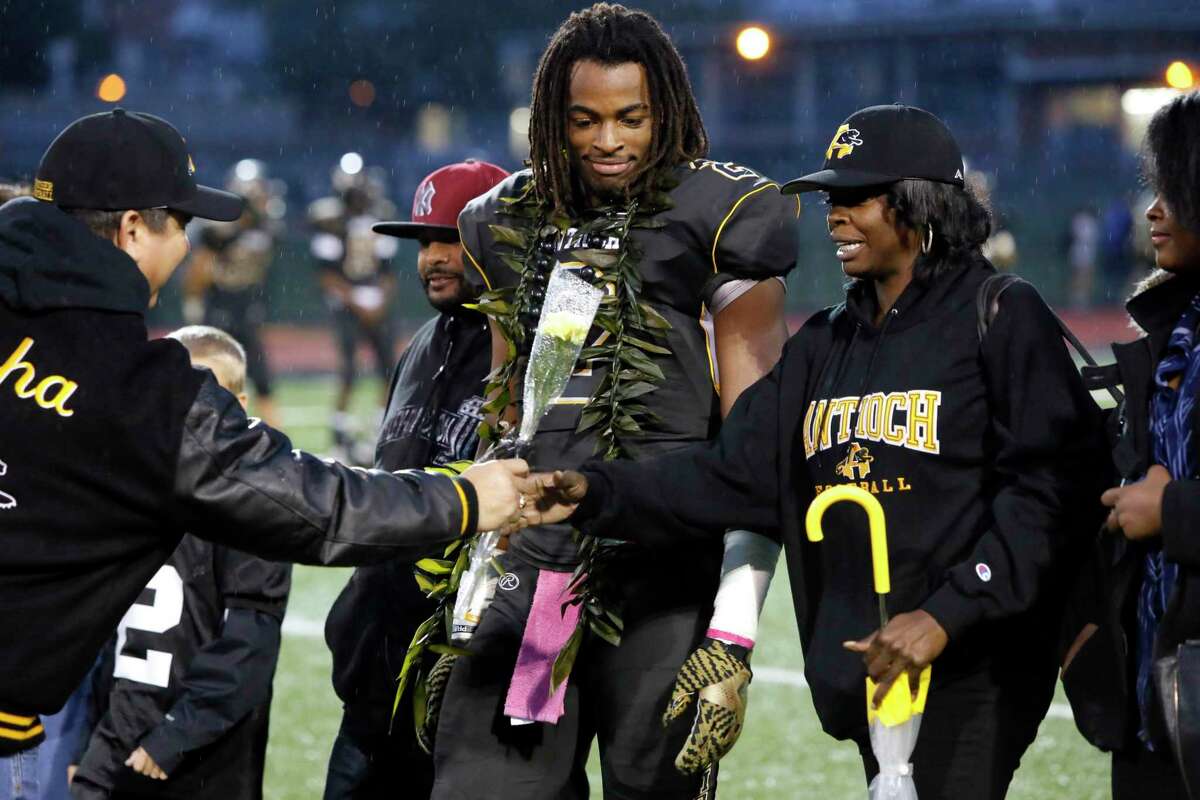 Seniors' night for the players as school principal Louie Rocha, (left) hands a flower to Tianna Hicks with her son Najee Harris , 2 close by as the Antioch Panthers prepare to take on the Heritage Patriots in Antioch, California on Friday October 28, 2016.