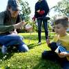 Marcie Lee takes a photo as her son Benjamin holds a piece of clover upon which his butterfly sat as they join in the butterfly release on the opening day of Shangri La's Eco-Fest 2021: Butterflies & Blooms, celebrating Earth Day. The event continues through Saturday. Photo made Thursday, April 22, 2021 Kim Brent/The Enterprise