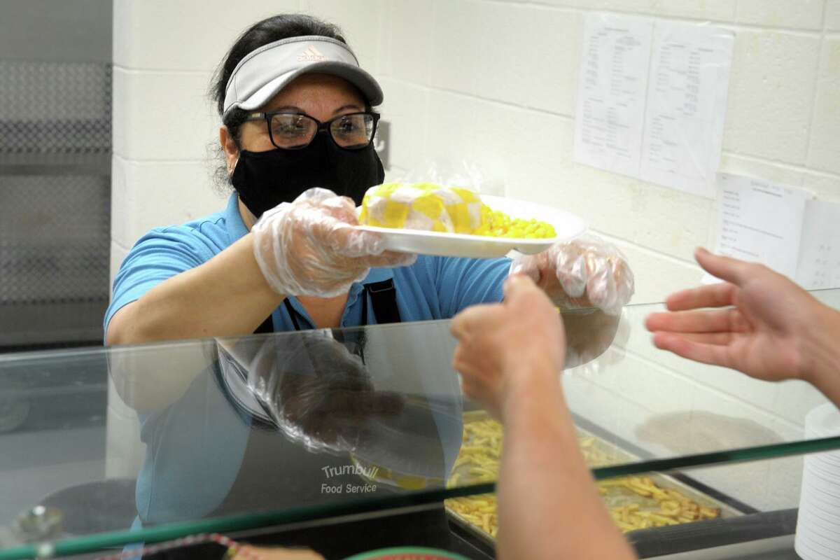 Tanya Zakhour serves hot meals to students in the cafeteria kitchen at Trumbull High School, in Trumbull, Conn. April 22, 2021.