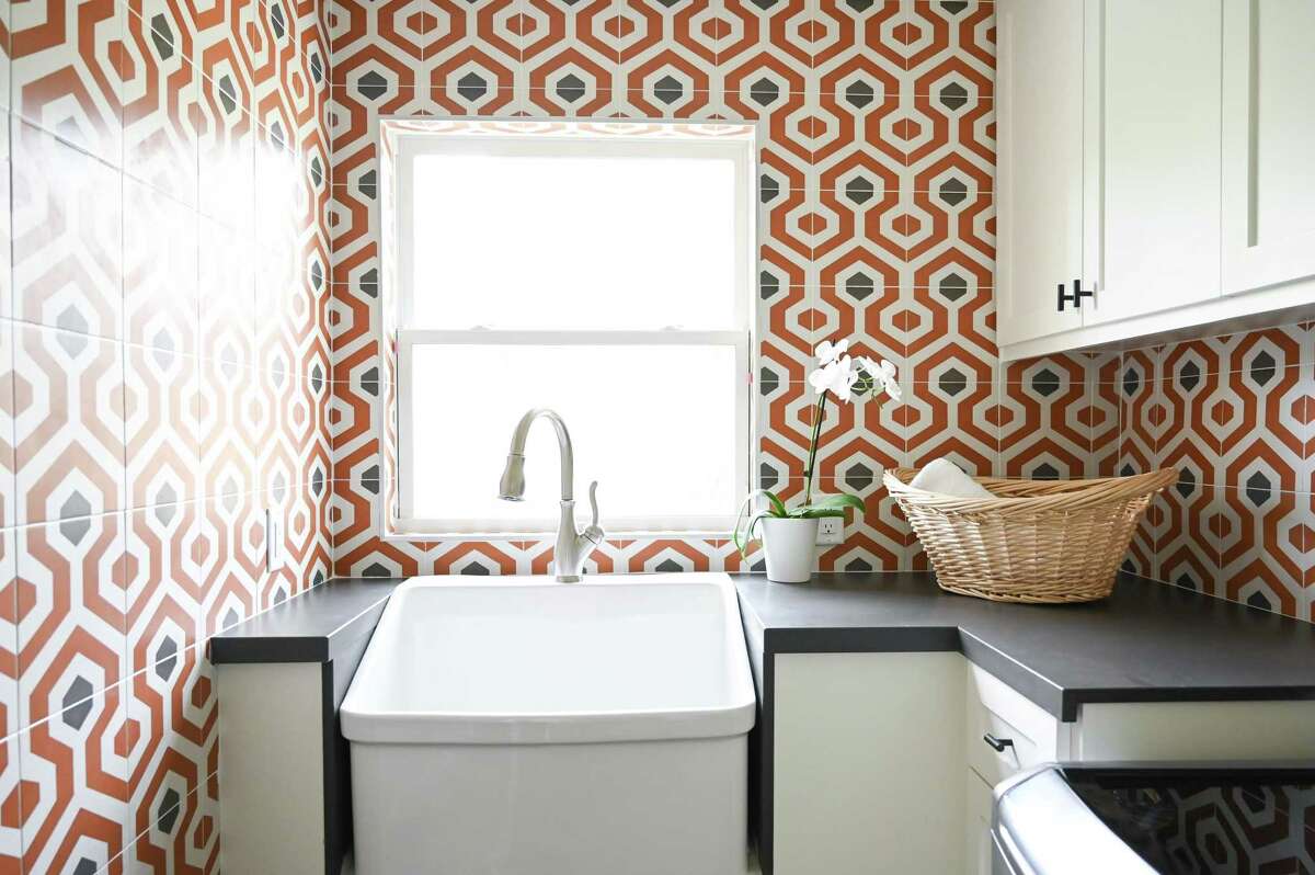 They create a laundy room out of some of the breakfast room, and a stylish nod to the mod colors of the 1960s — when the home was built — come in orange and gray tile.