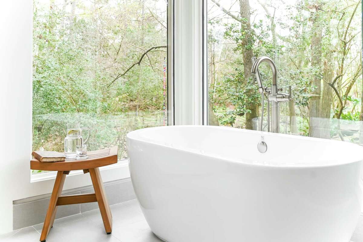 Large windows in the primary bathroom brighten up the space and provide a great view to the ravine below.