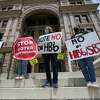 People opposed to Texas voter bills HB6 and SB7 hold signs during a news conference hosted by Texas Rising Action on the steps of the State Capitol, Wednesday, April 21, 2021, in Austin, Texas. (AP Photo/Eric Gay)