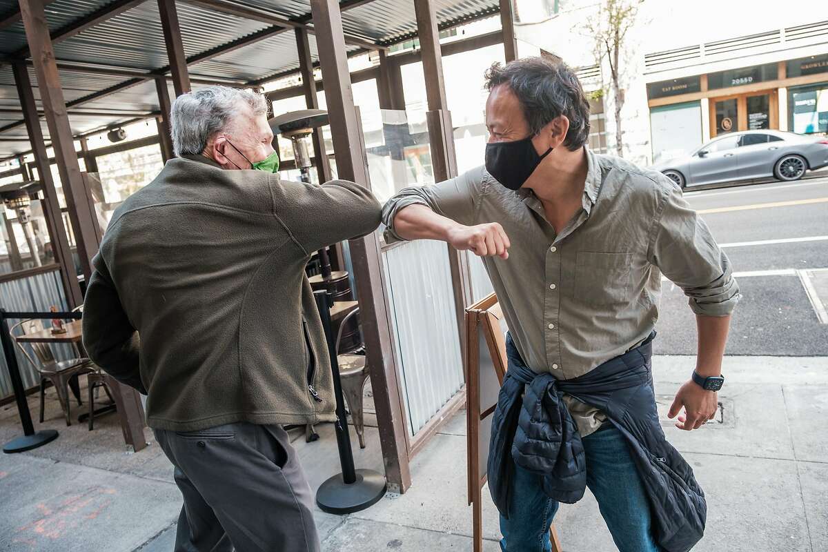 Stephen Shortell (left), former dean of the UC Berkeley School of Public Health, and current dean Dr. Michael Lu greet each other with an elbow bump at a Berkeley restaurant for the first time in more than a year.