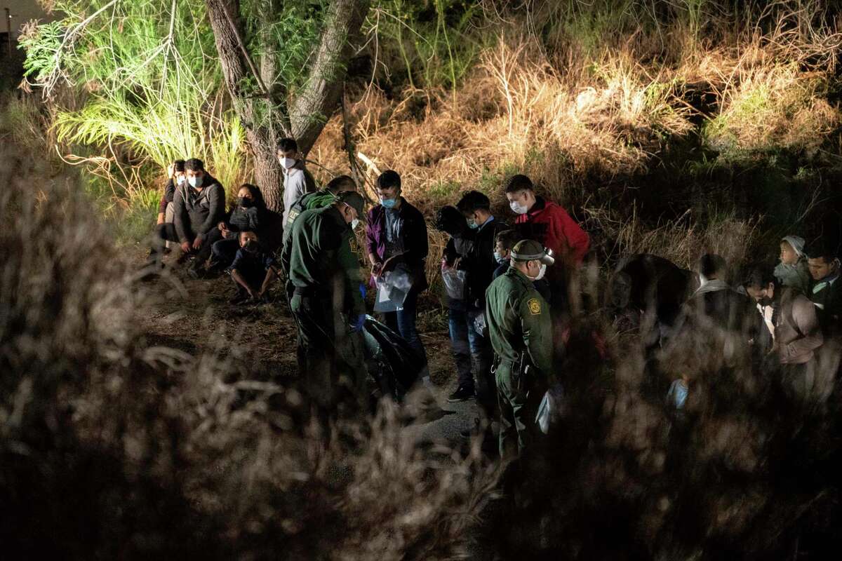 Asylum-seeking migrants' families wait to be transported by the U.S. Border Patrol after crossing the Rio Grande into the United States from Mexico on April 23, 2021 in Roma, Texas.