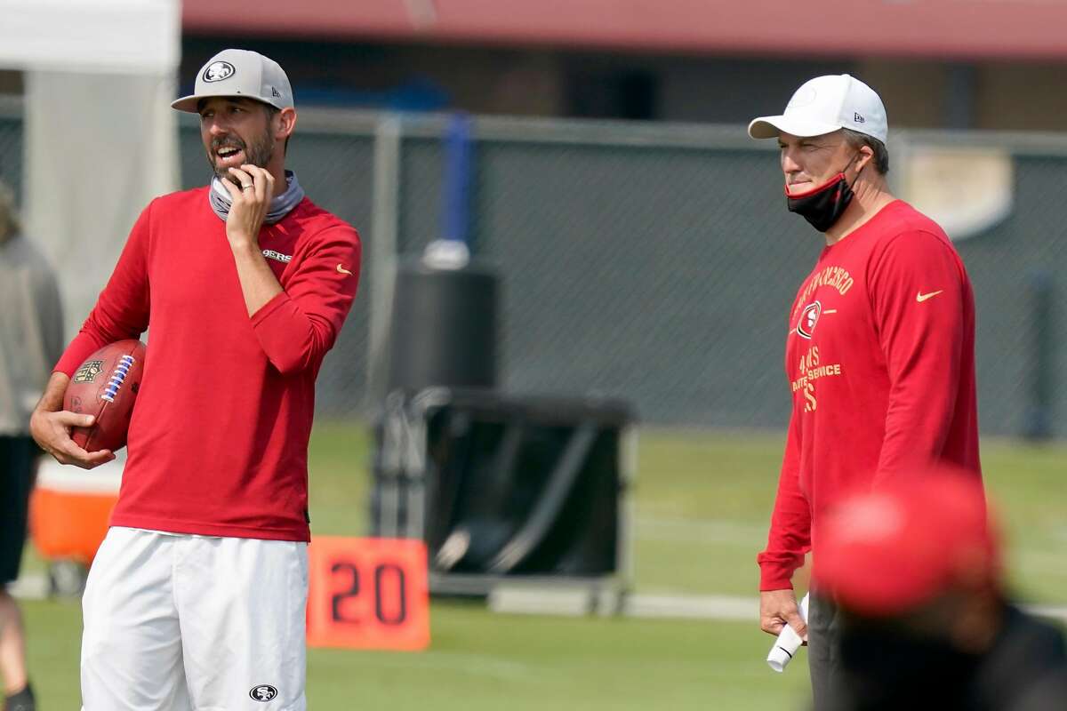 San Francisco 49ers general manager John Lynch, right, and head coach Kyle Shanahan watch players warm up during NFL football practice in Santa Clara, Calif., Sunday, Aug. 23, 2020.