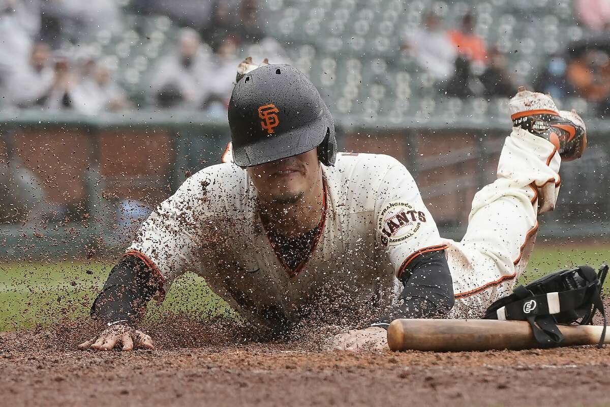 San Francisco Giants' Wilmer Flores slides home to score against the Miami Marlins during the second inning of a baseball game in San Francisco, Sunday, April 25, 2021.
