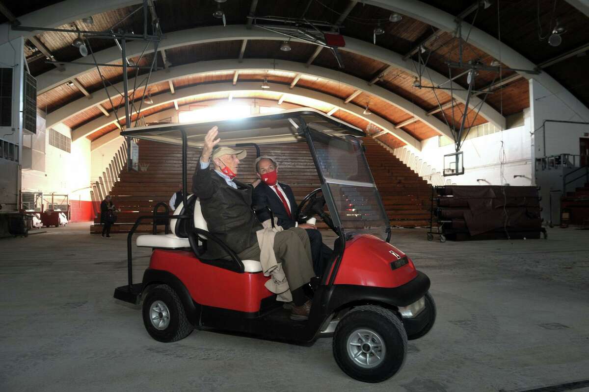 John Phelan, left, who worked as an architect to help design Alumni Hall, sits in a golf cart with Fairfield University President Mark Nemec as they join others for a final tour of the building in Fairfield, Conn. April 26, 2021. Built in 1959, demolition of the hall began Monday morning.