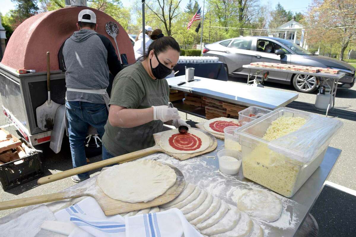 Alorfa Escoboda, from Bailey's Backyard Pizza Pop-Up, makes pizzas for the drive-thru senior lunch at Lounsbury House in Ridgefield, Conn, on Monday, April 26, 2021.