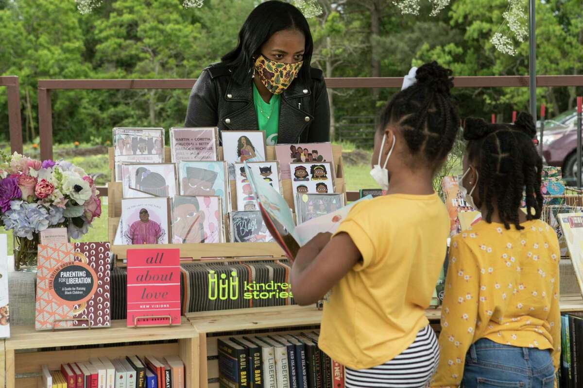 Terri Hamm helps sisters Noele and Taylor Harris on April 18 at Kindred Stories, a pop-up bookstore at Ivy Leaf Farms in Sunnyside.