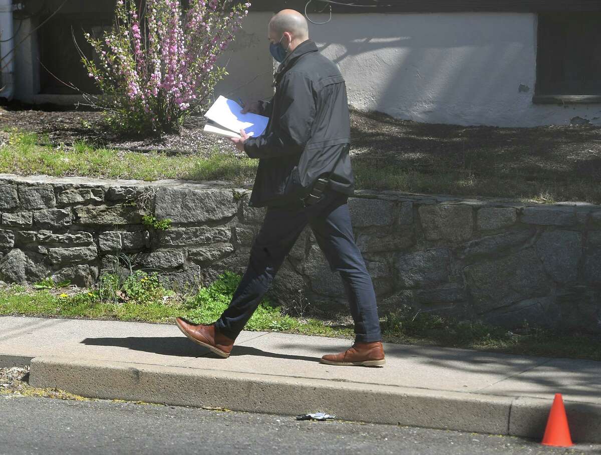 A state police investigator walks past a handgun at the scene of a 7 am police shooting involving a Derby police officer on Division Street in Ansonia, Conn. on Monday, April 26, 2021. Division Street marks the border between Ansonia and Derby.