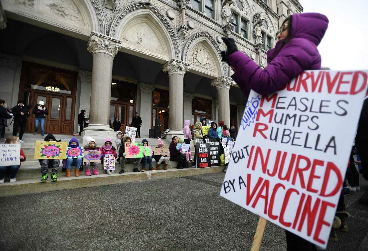 Anti-vaccine protesters line up children holding signs as a photo opportunity during a rally on the back steps of the Capitol during opening session of the state legislature in Hartford, Conn. on Wednesday, February 05, 2020.