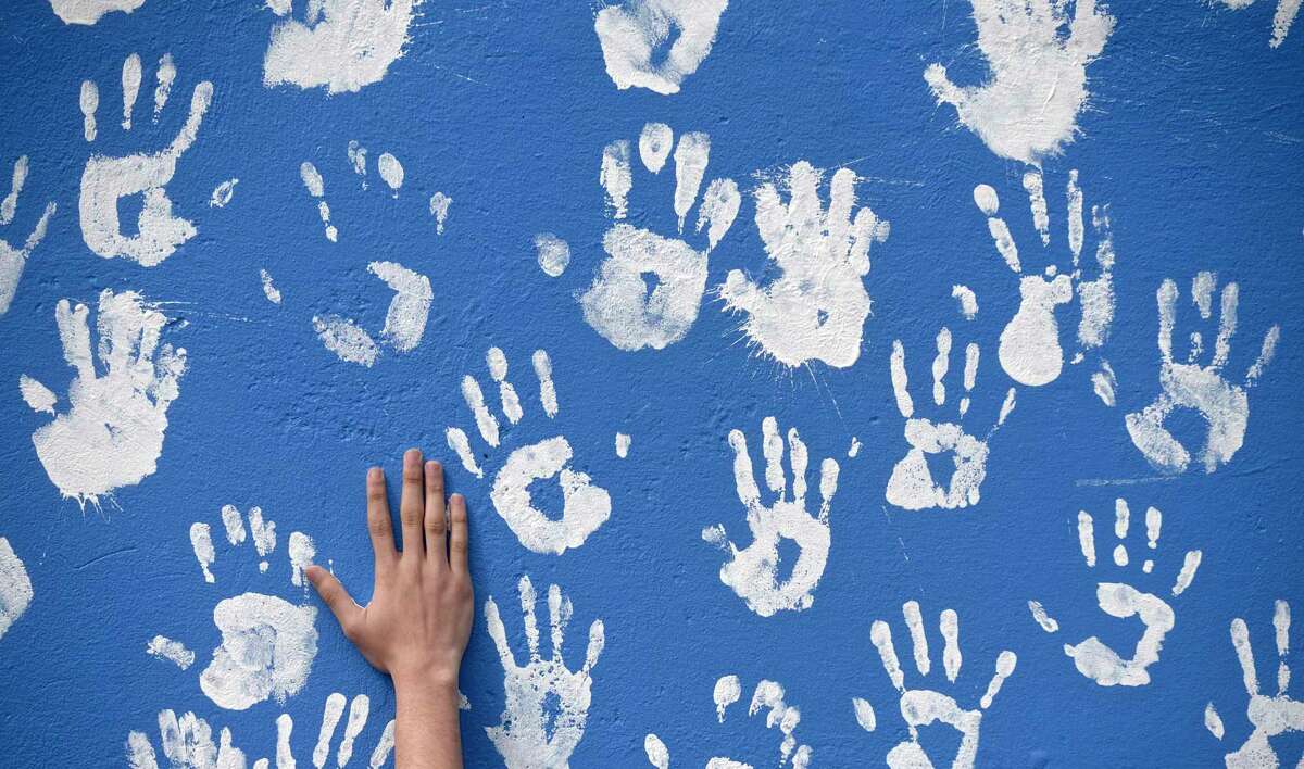 A senior from Danbury High School leaves their hand print on a mural honoring the Class of 2021on Tuesday morning, April, 27, 2021, in Danbury, Conn.