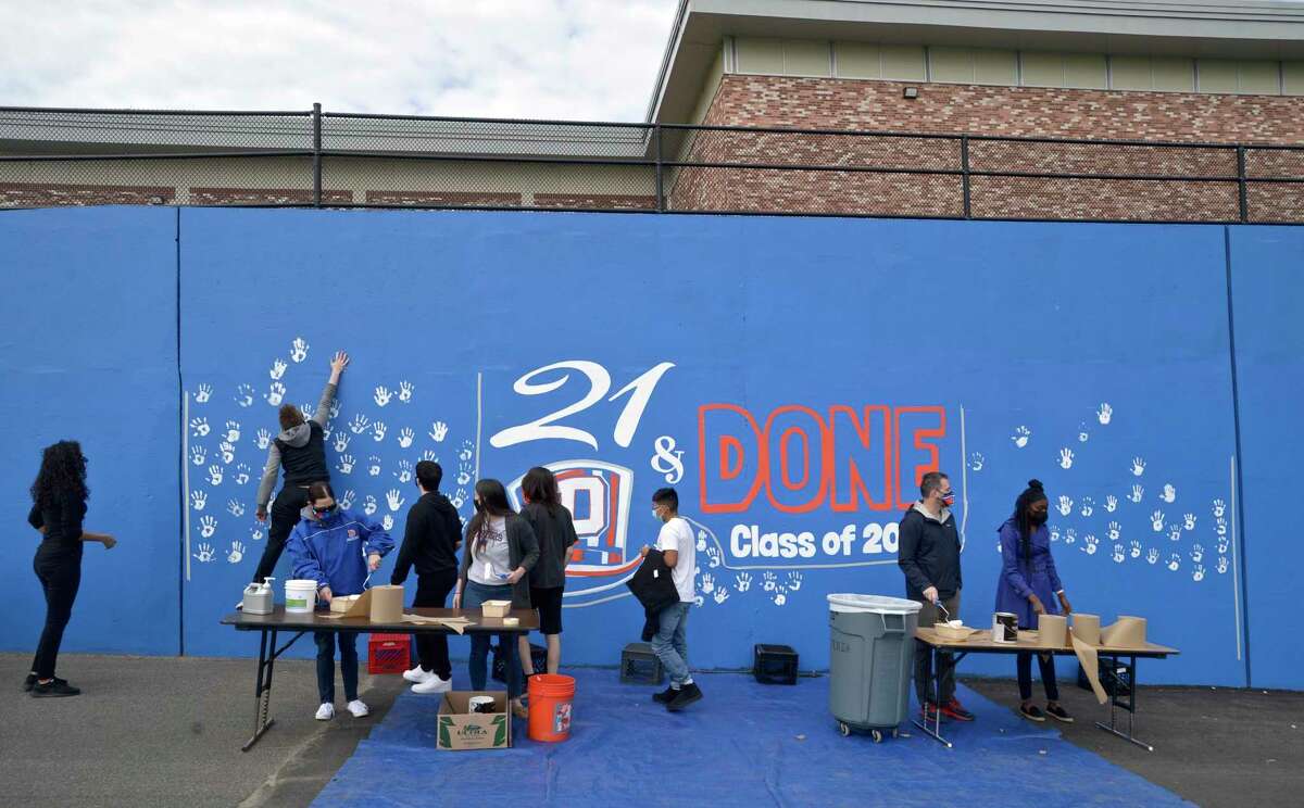 Seniors from Danbury High School leave their hand prints on a mural honoring the Class of 2021on Tuesday morning, April, 27, 2021, in Danbury, Conn.