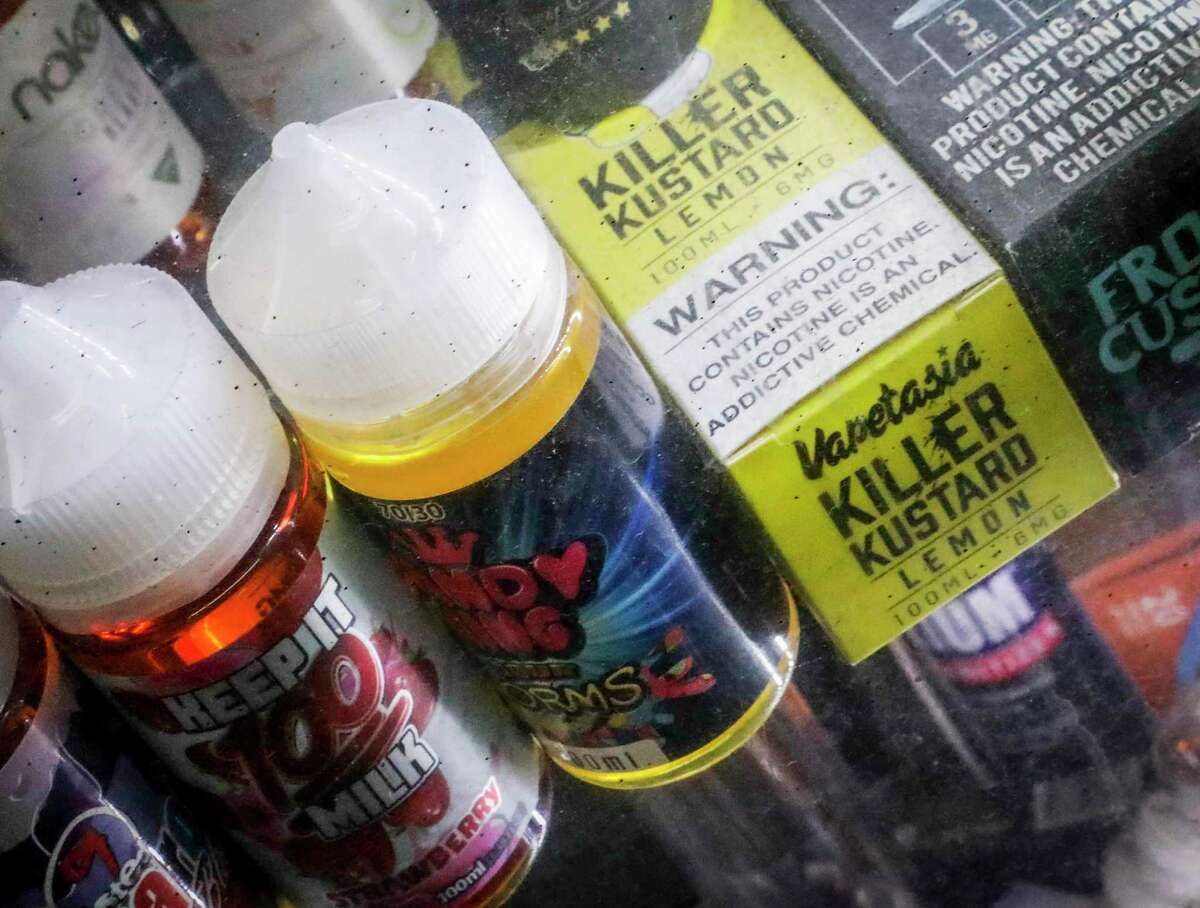 FILE- This Sept. 16, 2019 file photo shows flavored vaping solutions in a window display at a vape and smoke shop in New York.