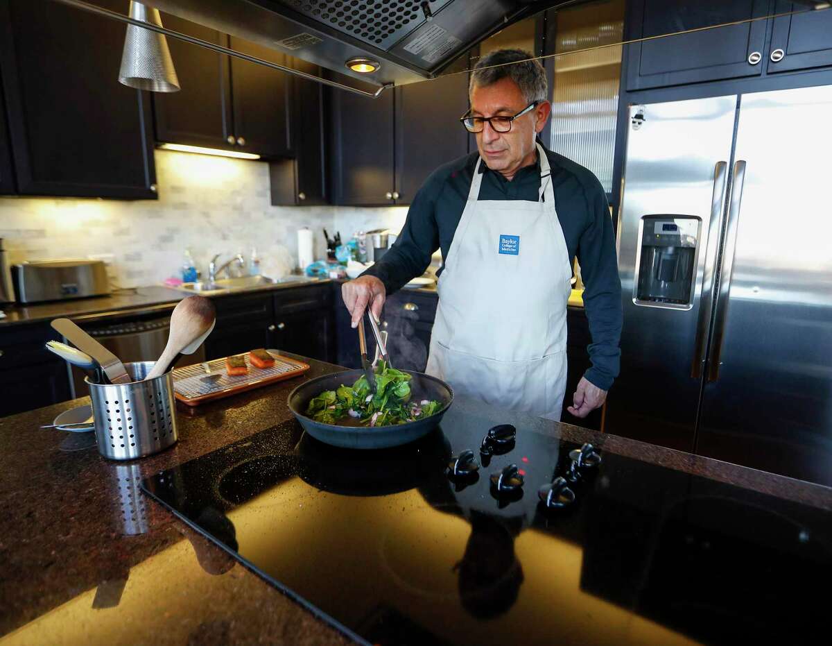 Dr. Paul Klotman, president and CEO of Baylor College of Medicine, cooks spinach and onion to go with his crispy salmon, in his kitchen, Thursday, March 18, 2021. Pre-covid, he was at a fine dining restaurant every night of the week. Xochi, Brennan's, DeMarco's and then his favorites in Manhattan, where he lives part of the month with his wife. Then the pandemic happened and it all changed. He had a bottle of wine and milk in his refrigerator. In the last year, Klotman has been sous vide cooking, he makes bread, he pickles vegetables and has started his own herb garden on his balcony. He took MasterClass cooking classes and orders specialty fish for elaborate dishes he wants to recreate. Cooking has become one of his outlets for stress relief, but he's looking forward to eating in more with friends and family once it's safe to do so.