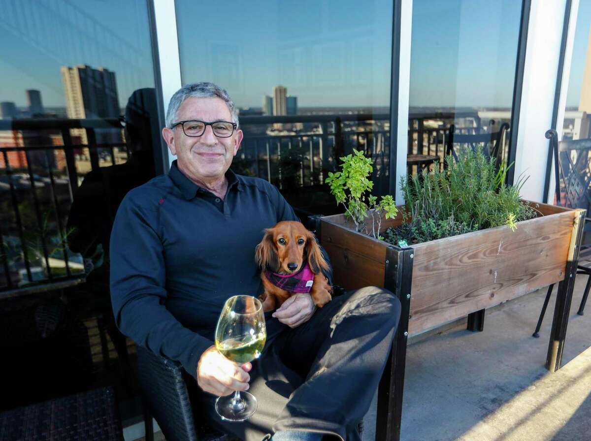 Dr. Paul Klotman, president and CEO of Baylor College of Medicine, sits with his dog, Lily as he enjoys a glass of wine next to his herb garden on his balcony, Thursday, March 18, 2021. Pre-covid, he was at a fine dining restaurant every night of the week. Xochi, Brennan's, DeMarco's and then his favorites in Manhattan, where he lives part of the month with his wife. Then the pandemic happened and it all changed. He had a bottle of wine and milk in his refrigerator. In the last year, Klotman has been sous vide cooking, he makes bread, he pickles vegetables and has started his own herb garden on his balcony. He took MasterClass cooking classes and orders specialty fish for elaborate dishes he wants to recreate. Cooking has become one of his outlets for stress relief, but he's looking forward to eating in more with friends and family once it's safe to do so.