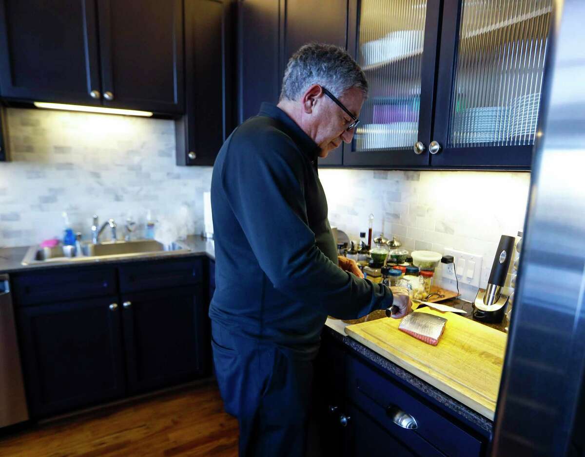 Dr. Paul Klotman, president and CEO of Baylor College of Medicine, prepares to cook crispy salmon in his kitchen, Thursday, March 18, 2021. Pre-covid, he was at a fine dining restaurant every night of the week. Xochi, Brennan's, DeMarco's and then his favorites in Manhattan, where he lives part of the month with his wife. Then the pandemic happened and it all changed. He had a bottle of wine and milk in his refrigerator. In the last year, Klotman has been sous vide cooking, he makes bread, he pickles vegetables and has started his own herb garden on his balcony. He took MasterClass cooking classes and orders specialty fish for elaborate dishes he wants to recreate. Cooking has become one of his outlets for stress relief, but he's looking forward to eating in more with friends and family once it's safe to do so.