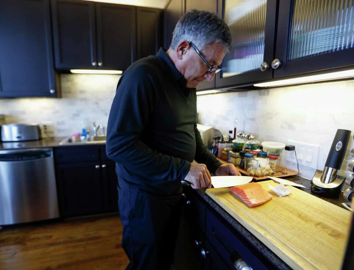Dr. Paul Klotman, president and CEO of Baylor College of Medicine, prepares to cook crispy salmon in his kitchen, Thursday, March 18, 2021. Pre-covid, he was at a fine dining restaurant every night of the week. Xochi, Brennan's, DeMarco's and then his favorites in Manhattan, where he lives part of the month with his wife. Then the pandemic happened and it all changed. He had a bottle of wine and milk in his refrigerator. In the last year, Klotman has been sous vide cooking, he makes bread, he pickles vegetables and has started his own herb garden on his balcony. He took MasterClass cooking classes and orders specialty fish for elaborate dishes he wants to recreate. Cooking has become one of his outlets for stress relief, but he's looking forward to eating in more with friends and family once it's safe to do so.