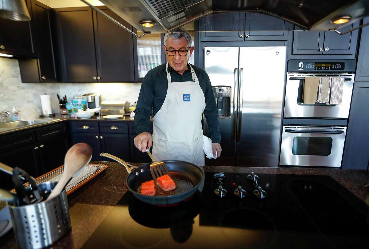 Dr. Paul Klotman, president and CEO of Baylor College of Medicine, cooks crispy salmon in his kitchen, Thursday, March 18, 2021. Pre-covid, he was at a fine dining restaurant every night of the week. Xochi, Brennan's, DeMarco's and then his favorites in Manhattan, where he lives part of the month with his wife. Then the pandemic happened and it all changed. He had a bottle of wine and milk in his refrigerator. In the last year, Klotman has been sous vide cooking, he makes bread, he pickles vegetables and has started his own herb garden on his balcony. He took MasterClass cooking classes and orders specialty fish for elaborate dishes he wants to recreate. Cooking has become one of his outlets for stress relief, but he's looking forward to eating in more with friends and family once it's safe to do so.