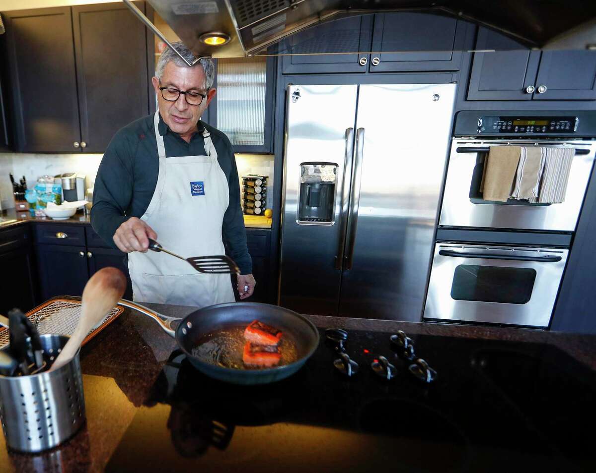 Dr. Paul Klotman, president and CEO of Baylor College of Medicine, cooks crispy salmon in his kitchen, Thursday, March 18, 2021. Pre-covid, he was at a fine dining restaurant every night of the week. Xochi, Brennan's, DeMarco's and then his favorites in Manhattan, where he lives part of the month with his wife. Then the pandemic happened and it all changed. He had a bottle of wine and milk in his refrigerator. In the last year, Klotman has been sous vide cooking, he makes bread, he pickles vegetables and has started his own herb garden on his balcony. He took MasterClass cooking classes and orders specialty fish for elaborate dishes he wants to recreate. Cooking has become one of his outlets for stress relief, but he's looking forward to eating in more with friends and family once it's safe to do so.