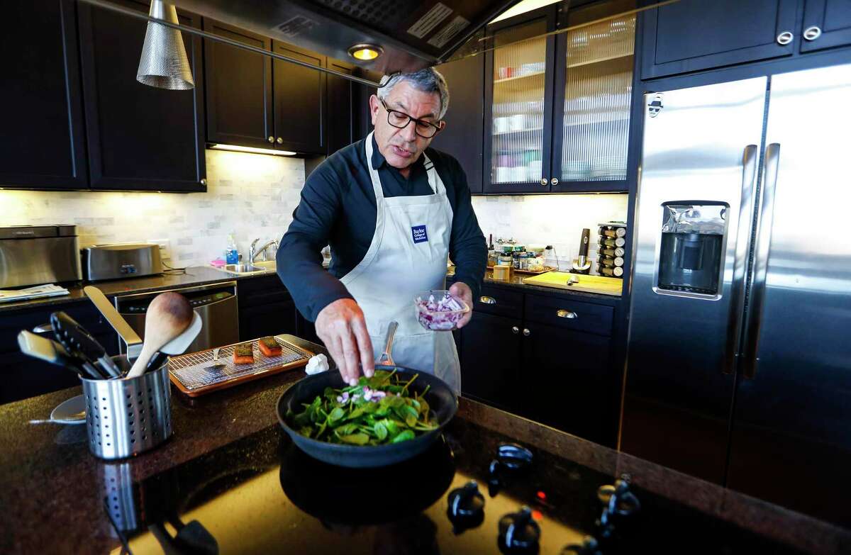 Dr. Paul Klotman, Baylor College of Medicine president and CEO, cooks spinach, onion and crispy salmon in his kitchen.
