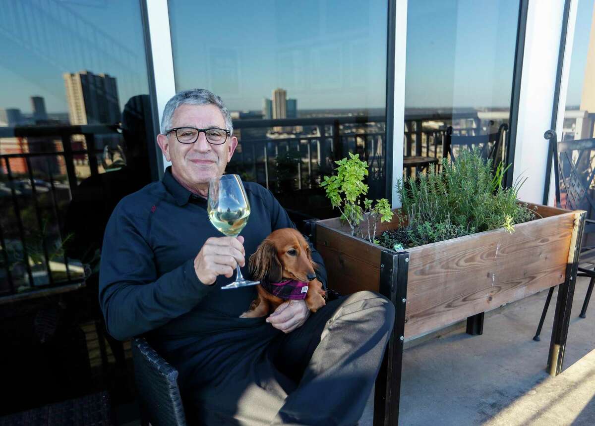 Dr. Paul Klotman, president and CEO of Baylor College of Medicine, sits with his dog, Lily as he enjoys a glass of wine next to his herb garden on his balcony, Thursday, March 18, 2021. Pre-covid, he was at a fine dining restaurant every night of the week. Xochi, Brennan's, DeMarco's and then his favorites in Manhattan, where he lives part of the month with his wife. Then the pandemic happened and it all changed. He had a bottle of wine and milk in his refrigerator. In the last year, Klotman has been sous vide cooking, he makes bread, he pickles vegetables and has started his own herb garden on his balcony. He took MasterClass cooking classes and orders specialty fish for elaborate dishes he wants to recreate. Cooking has become one of his outlets for stress relief, but he's looking forward to eating in more with friends and family once it's safe to do so.