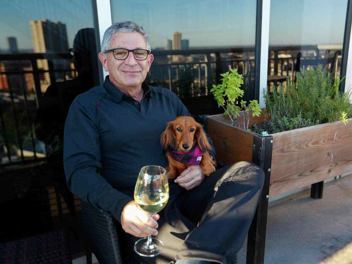 Dr. Paul Klotman, president and CEO of Baylor College of Medicine, sits with his dog, Lily as he enjoys a glass of wine next to his herb garden on his balcony, Thursday, March 18, 2021. Pre-covid, he was at a fine dining restaurant every night of the week. Xochi, Brennan's, DeMarco's and then his favorites in Manhattan, where he lives part of the month with his wife. Then the pandemic happened and it all changed. He had a bottle of wine and milk in his refrigerator. In the last year, Klotman has been sous vide cooking, he makes bread, he pickles vegetables and has started his own herb garden on his balcony. He took MasterClass cooking classes and orders specialty fish for elaborate dishes he wants to recreate. Cooking has become one of his outlets for stress relief, but he's looking forward to eating in more with friends and family once it's safe to do so.