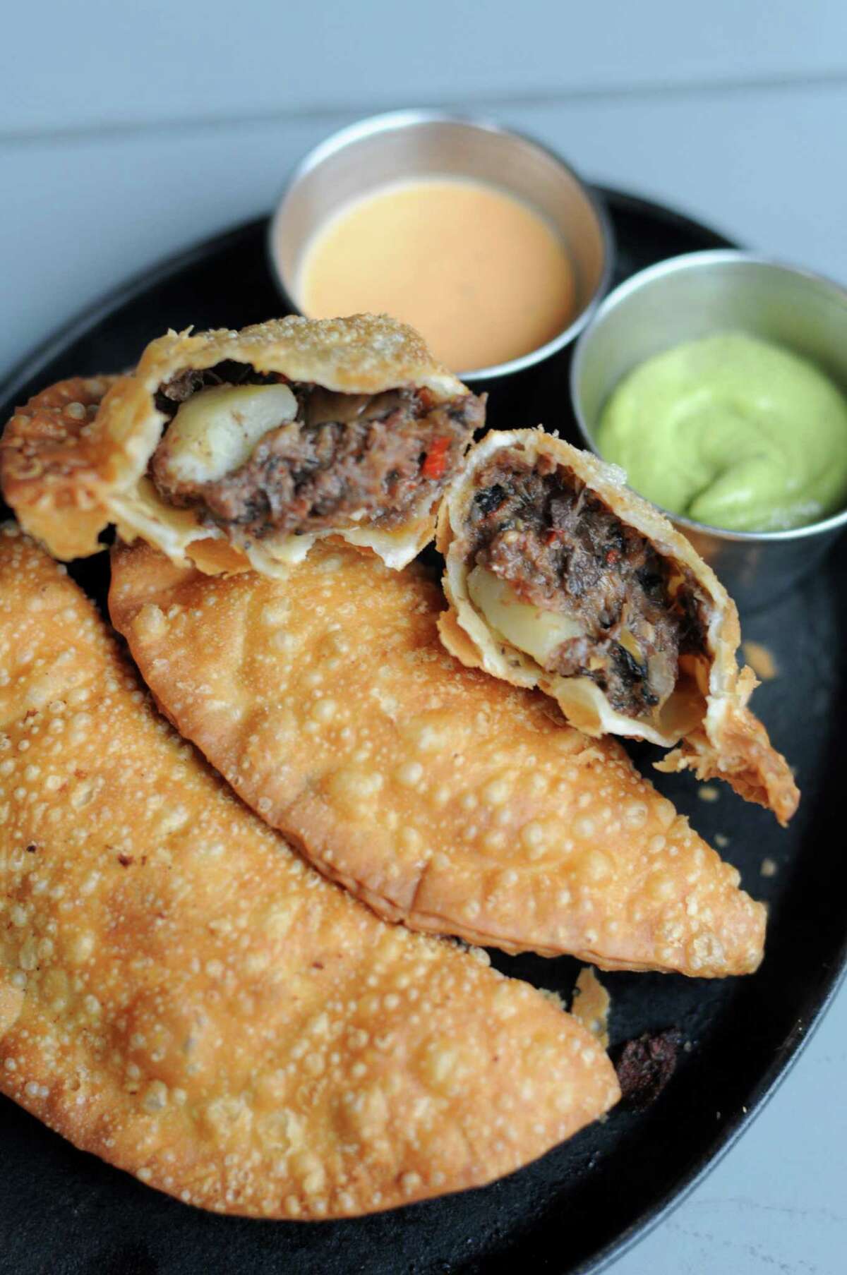 The barbacoa empanadas at Botika are stuffed with braised beef cheeks, olives, roasted peppers and potato.
