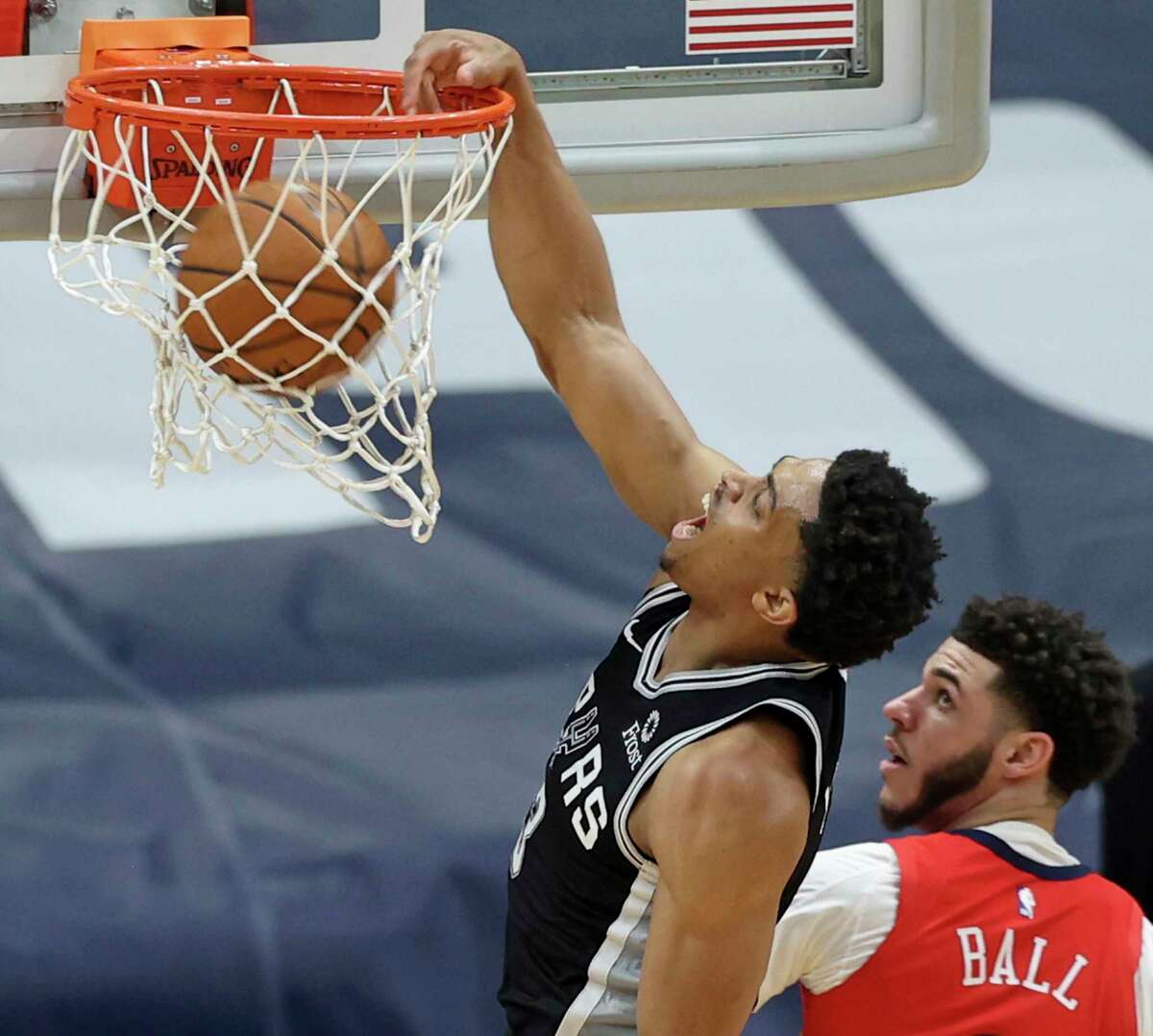 Spurs forward Keldon Johnson (3) dunks the ball as Pelicans guard Lonzo Ball (2) defends in the first half of an NBA basketball game in New Orleans, Saturday, April 24, 2021.