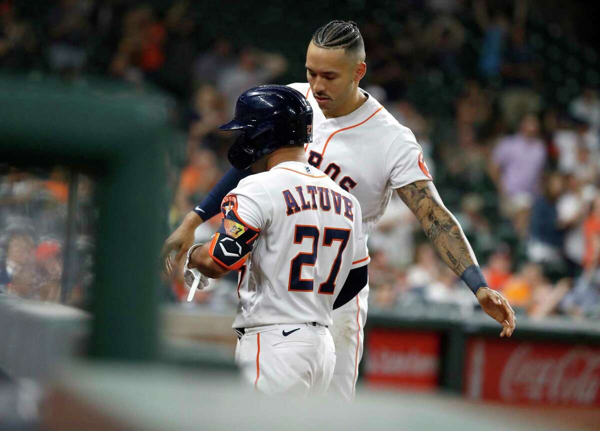 Houston Astros Carlos Correa (1) congratulates Jose Altuve after his sac fly scored Aledmys Diaz during the eighth inning of an MLB baseball game at Minute Maid Park, Wednesday, April 28, 2021, in Houston.