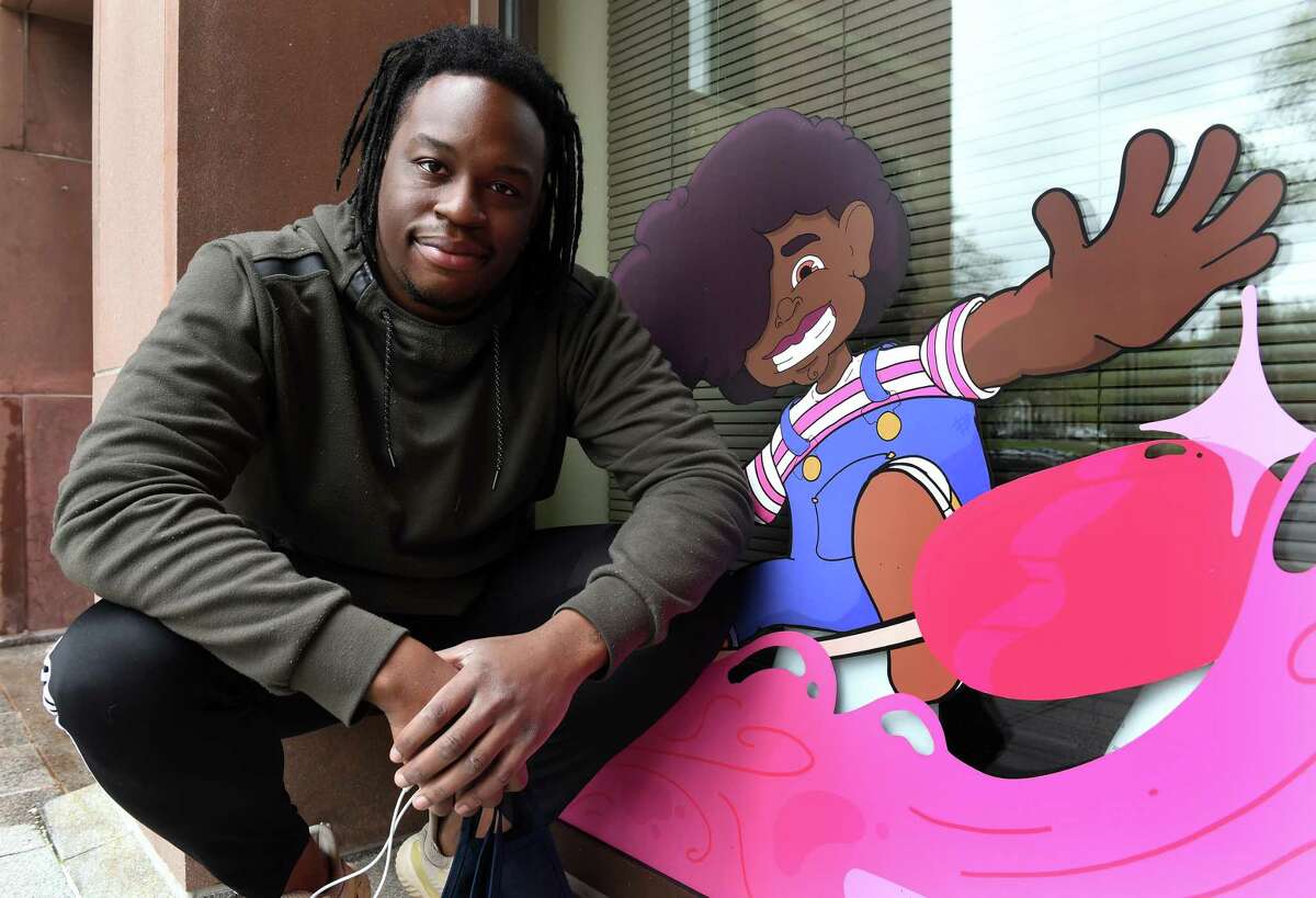 Artist Isaac Bloodworth of New Haven is photographed next to the character, Joy, he created on display as part of a larger mural at City Hall in New Haven on April 16, 2021.