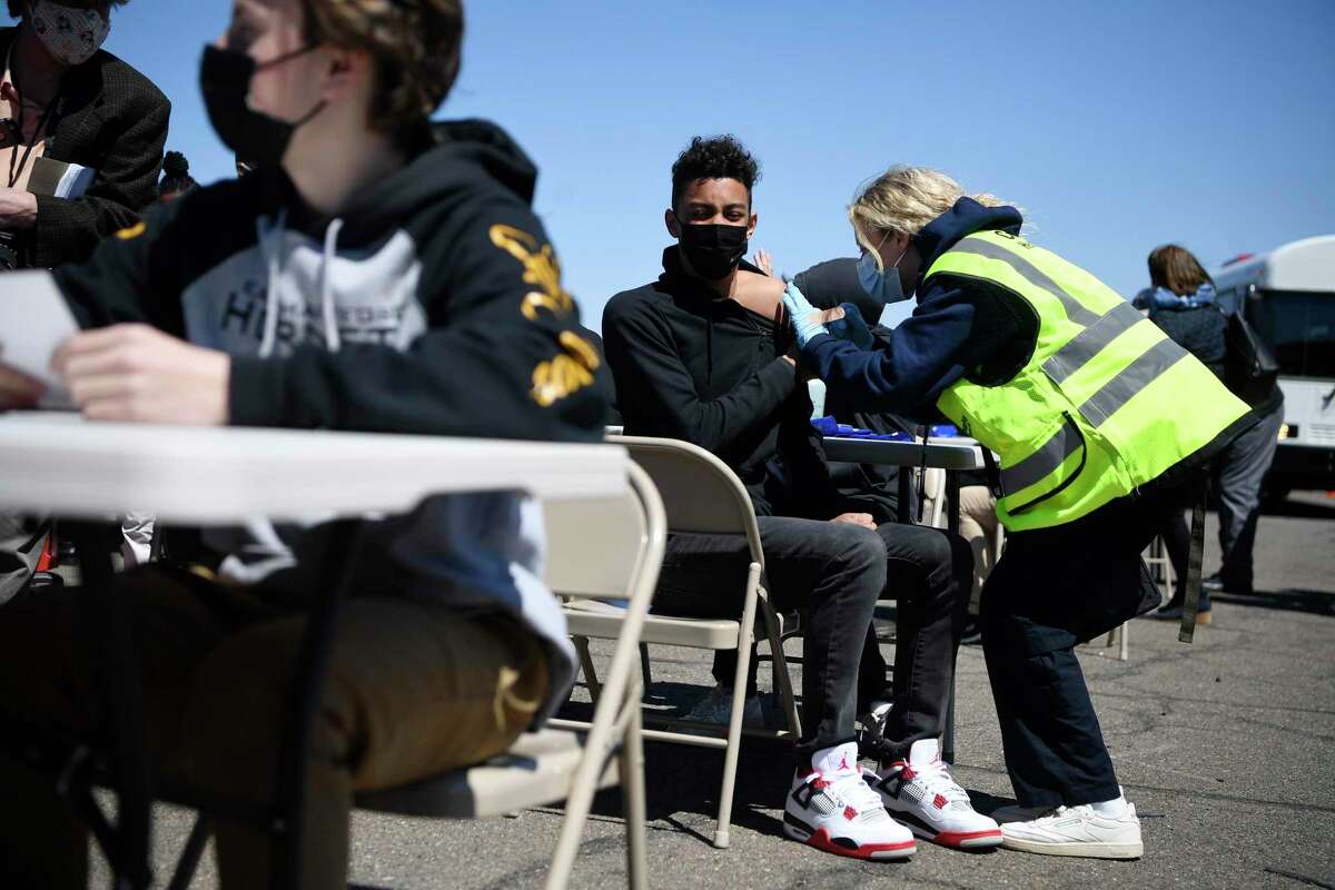 East Hartford High School junior Zander Robinson receives a vaccination from EMT Mary Kate Staunton of Clinton at a mass vaccination site at Pratt & Whitney runway in East Hartford this week.
