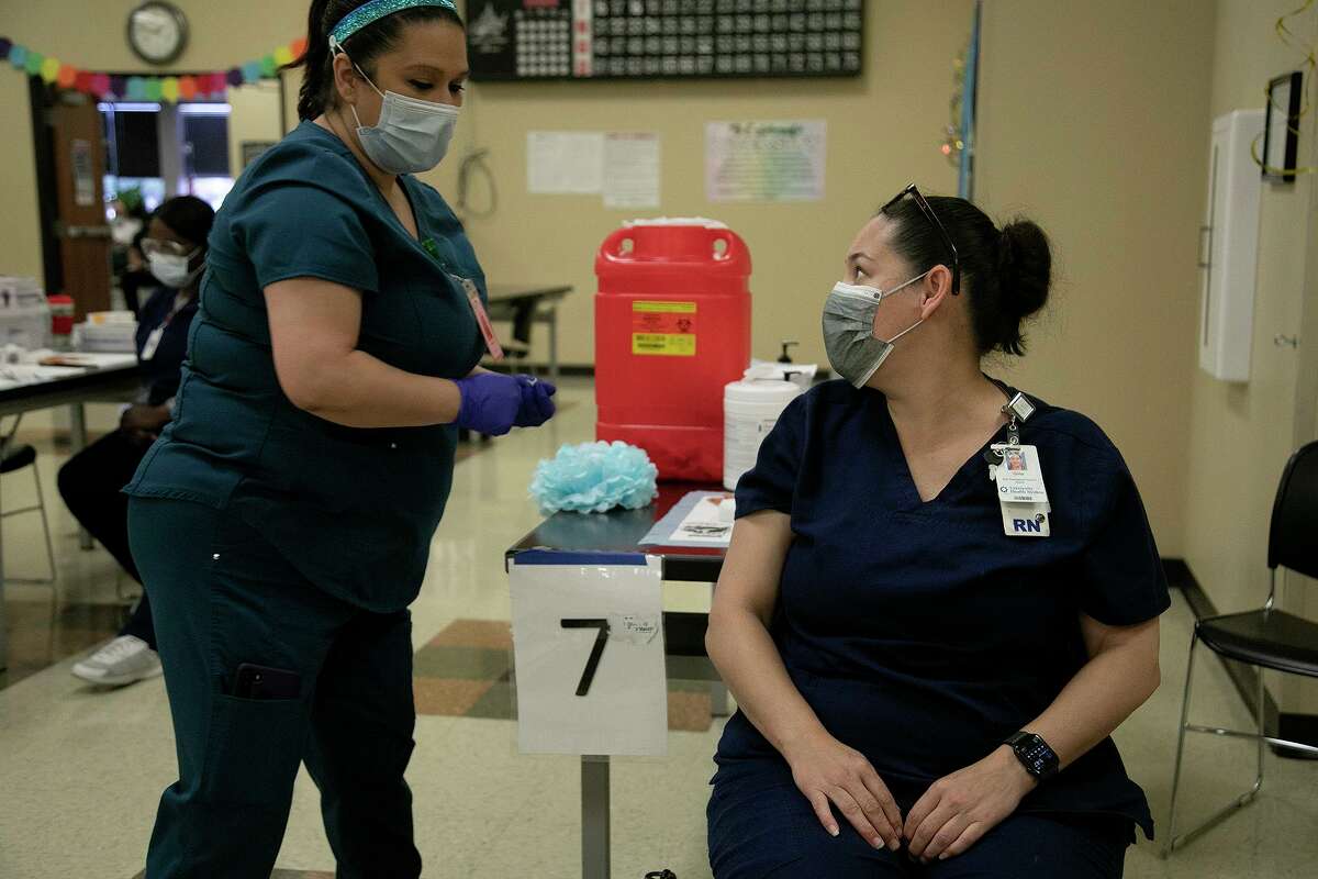 Gina Huron, right, a nurse with University Hospital’s Transplant Center, looks back at medical assistant Melissa Lara after Lara gave Huron the Johnson & Johnson COVID-19 vaccine. In Bexar County, 571,530 residents, or 38 percent of the population, are fully vaccinated, officials say.