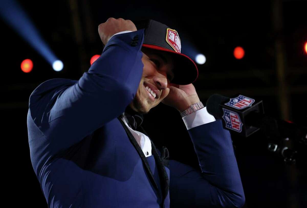 Trey Lance speaks puts on a 49ers cap after he was selected by the team as their top pick during the NFL draft in Cleveland.