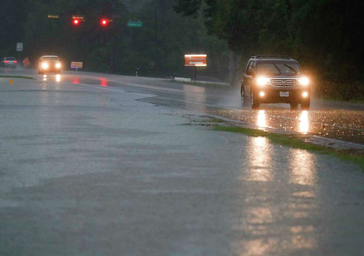 Vehicles drive down FM 1314 as heavy rains begin to flood portions of the road on Friday in Conroe. Heavy rainfall moved into Montgomery County early Friday morning, prompting local officials to issue warnings about flooding and reminders to avoid driving into low lying areas.