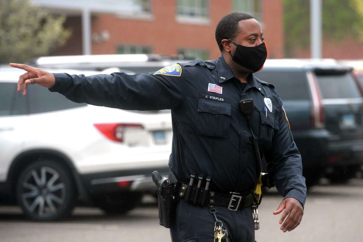 Shelton Police Officer John Staples directs traffic as school lets out at Perry Hill School, in Shelton, Conn. April 29, 2021.