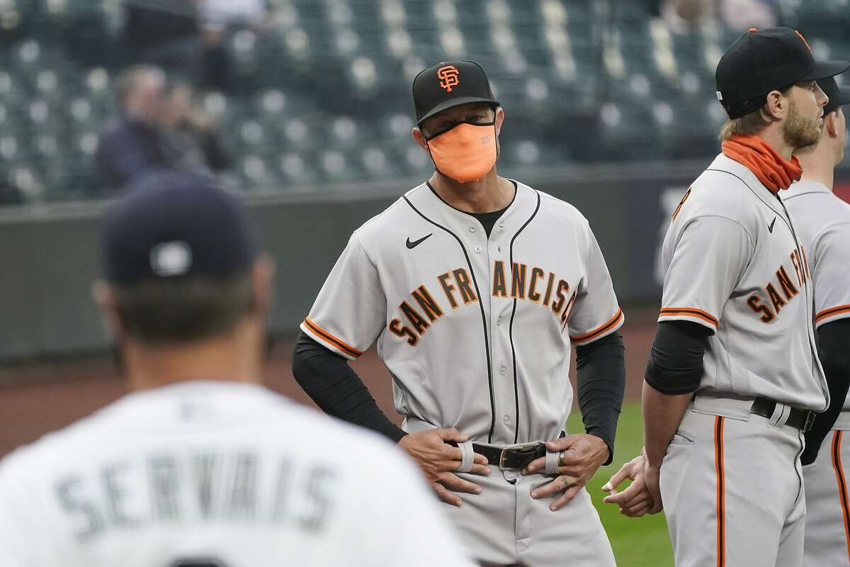 San Francisco Giants manager Gabe Kapler looks on as Seattle Mariners manager Scott Servais (9) turns toward him before a baseball game Thursday, April 1, 2021, in Seattle. (AP Photo/Elaine Thompson)
