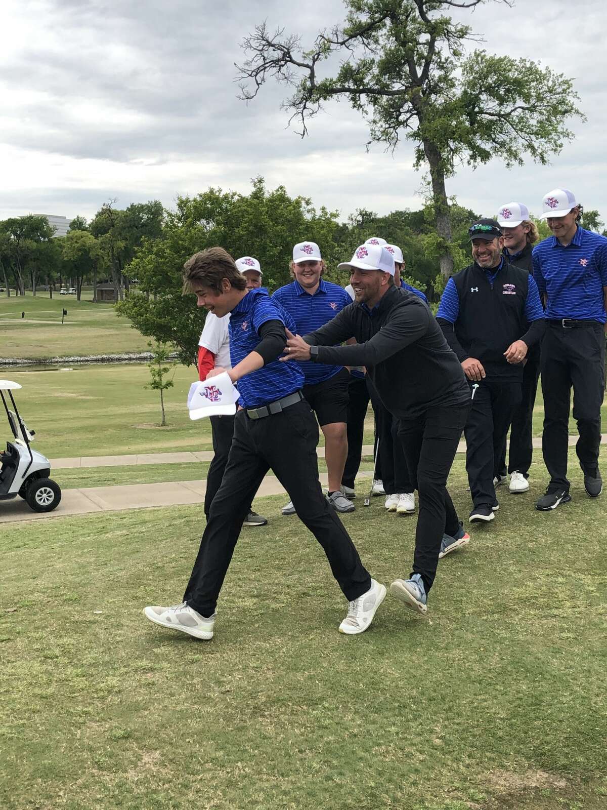 Midland Christian coach Trent Langford, center, celebrates with golfer Jake Humble and the rest of the Midland Christian boys golf team on April 21 at Sherrill Park Golf Course in Richardson after qualifying for the TAPPS 6A State Tournament.