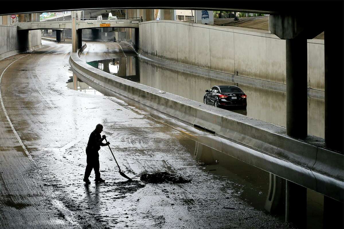 A San Antonio police officer shovels mud off Interstate 35 under San Pedro Avenue on Saturday, May 1, 2021. The highway had to be closed because of flooding from heavy rains in the area.