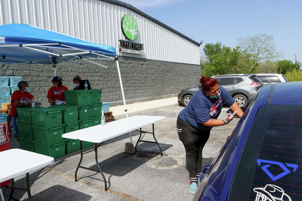 Joyce Moreno, right, with Be A Champion Inc., works with others, including volunteers from The Tree Mount Temple Church, to hand out food for children in front of the church at 6035 Seguin Road last month.