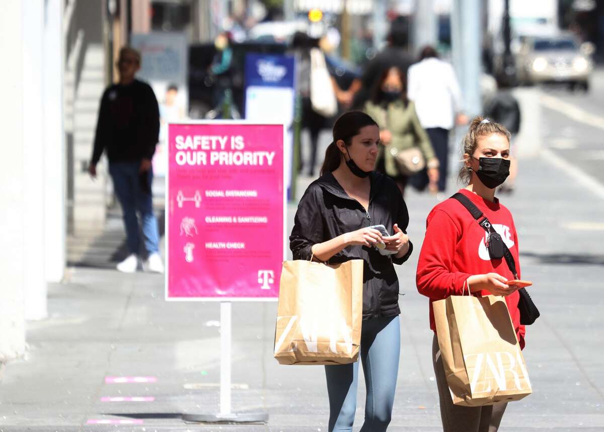 Pedestrians carry shopping bags as they walk through the Union Square shopping district on April 15, 2021, in San Francisco.