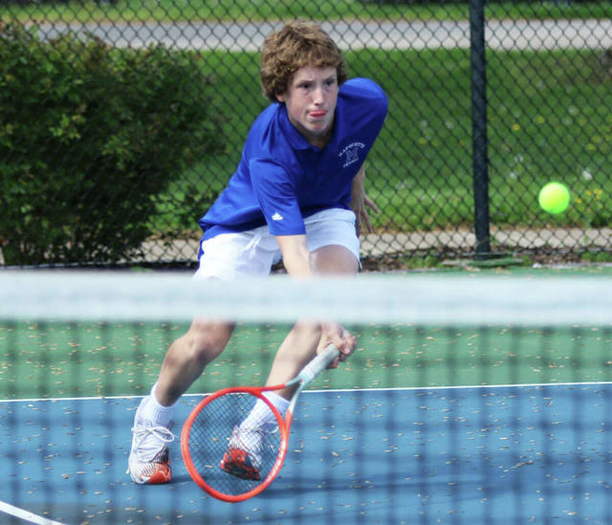 Marquette Catholic freshman Bradley Bower rushes toward the net to hit a return in his No. 1 singles victory against the Alton Redbirds on Thursday at Moore Park’s Simpson Tennis Center in Alton.