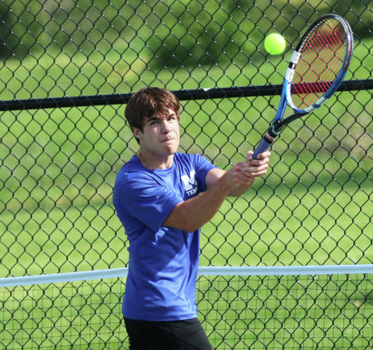 Marquette’s Marc Tassinari reaches up to hit a backhand in a No. 3 singles match against Alton on Thursday at Moore Park’s Simpson Tennis Center in Alton. Tassinari is the lone senior on the Explorers’ roster.