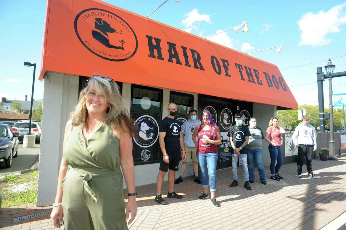 Owner Sandra DeRosa Briggs stands with members of her staff in front of Hair of the Dog, in Milford on Friday.