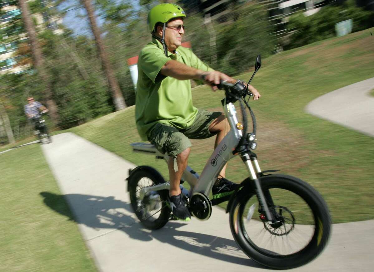 Advocates of electric bicycles, stand-up scooters and skateboard-like vehicles want The Woodlands to change a policy that bans motorized vehicles on the more than 200 miles of walking and bicycling paths. In this file image, Robert Solana, owner of ECO EZ-Riders in The Woodlands, demonstrates one of the company's electric bicycles. However, Solana no longer rents the ‘e-bikes.’