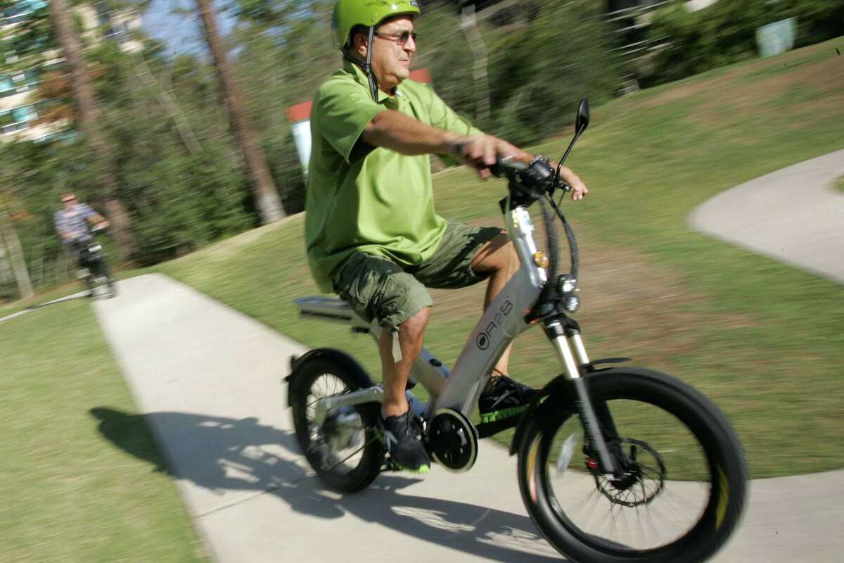 Advocates of electric bicycles, stand-up scooters and skateboard-like vehicles want The Woodlands to change a policy that bans motorized vehicles on the more than 200 miles of walking and bicycling paths. In this file image, Robert Solana, owner of ECO EZ-Riders in The Woodlands, demonstrates one of the company's electric bicycles. However, Solana no longer rents the ‘e-bikes.’