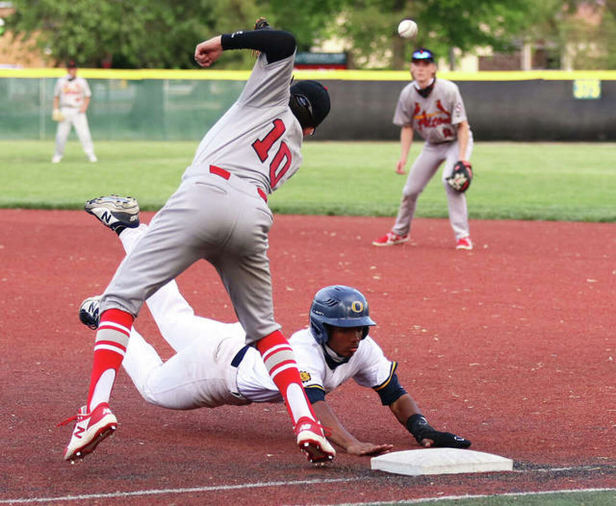 O'Fallon's Kellen Scruggs dives back to the bag while Alton first baseman Owen Macias (10) cannot get to a high and wide pickoff throw Monday at Blazier Field in O'Fallon.