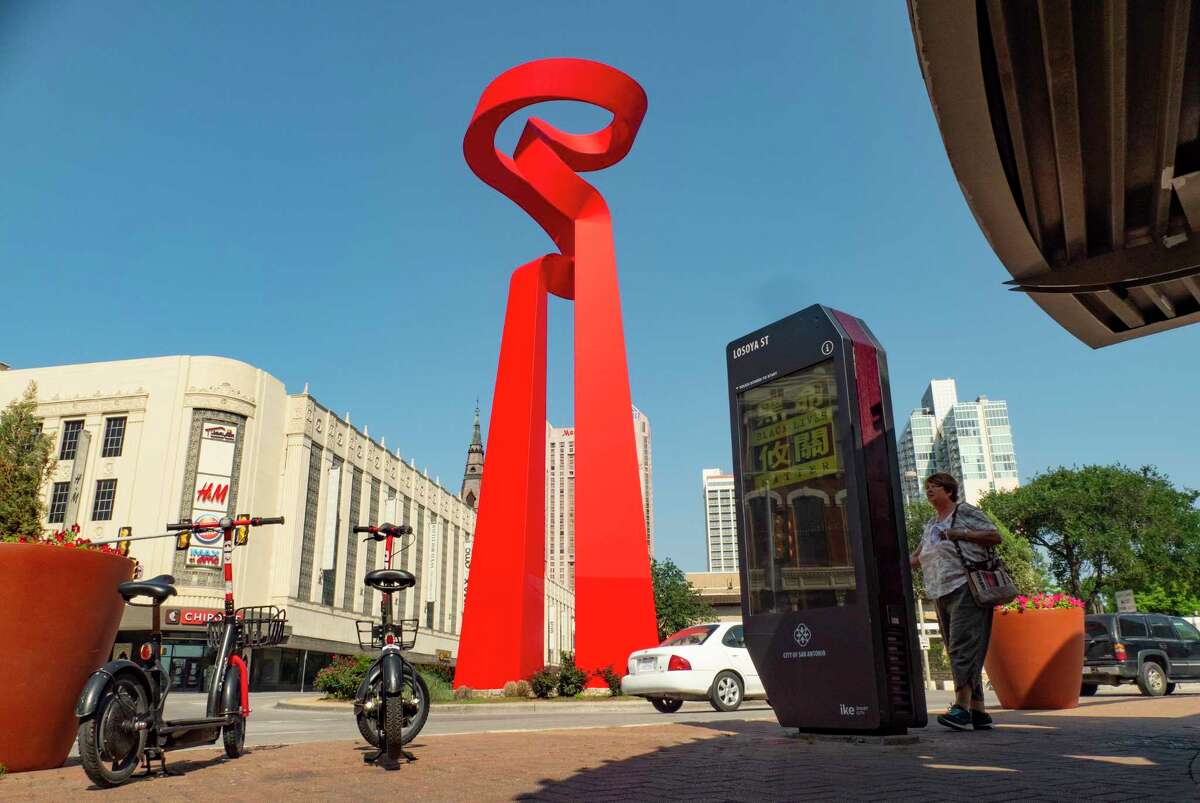 Debbie St. Clair uses an IKE kiosk in downtown San Antonio to find information on Monday, May 3, 2021. The City of San Antonio uses the kiosks to deliver information to pedestrians, both locals and tourists. The sculpture called “La Antorcha de la Amistad” by Mexican artist Sebastián, is at right.