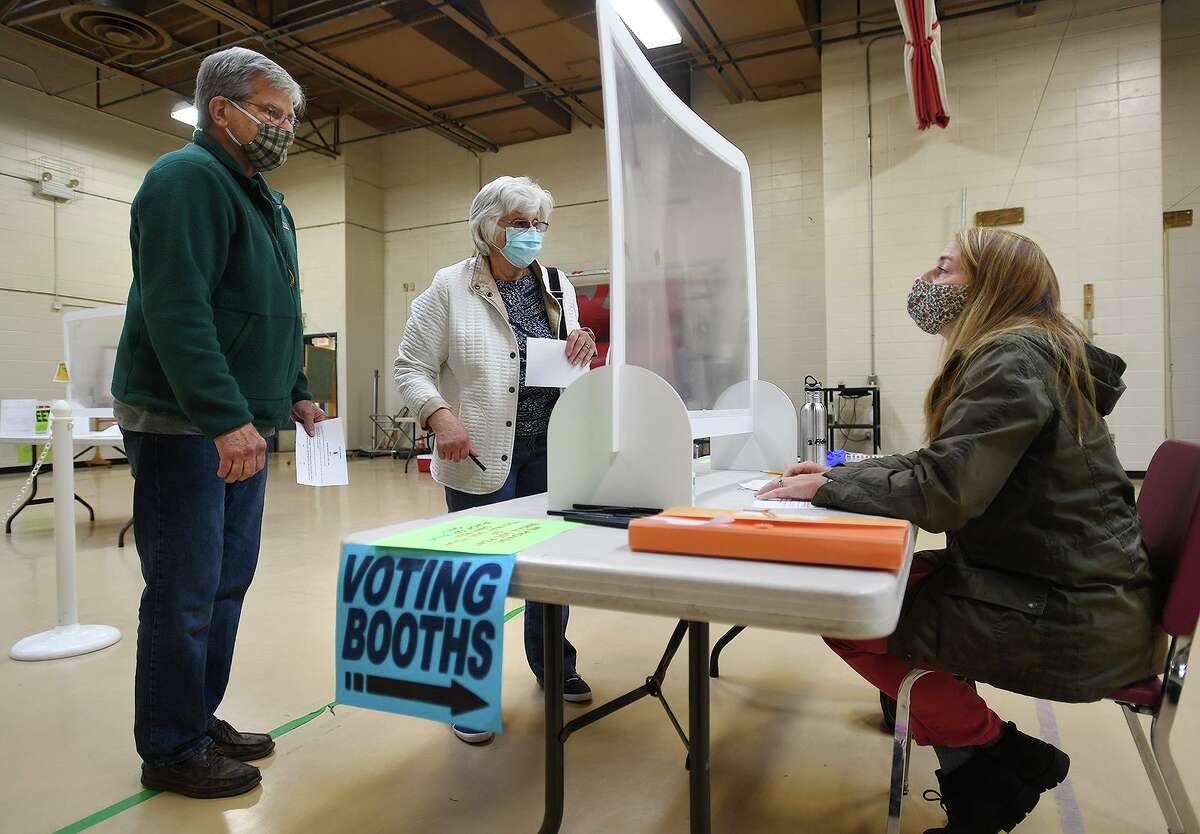 Ken and Pat Piddington, of Monroe, check in to vote on the town budget referendum with ballot clerk Ilona Palomba at Masuk High School in Monroe, Conn. on Tuesday, May 4, 2021.